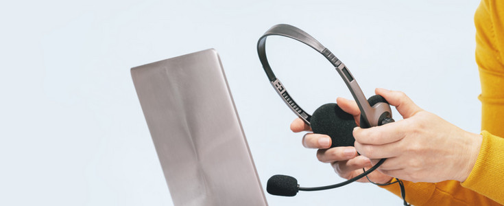 Laptop. headphones or headset on desk and plain background. Female hands over laptop. Distant learning or working from home, online courses or support concept. Helpdesk or call center operator © Laptop with headphones on wooden desk. Female hands